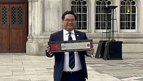 Dr. Glenn Agung Hole holding the Freedom of the City of London scroll outside Guildhall