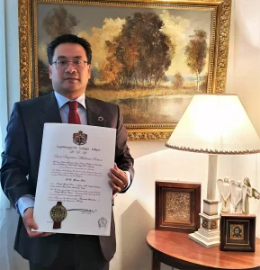 Dr. Glenn Agung Hole holding the diploma of the Grand Cross of the Eagle of Georgia